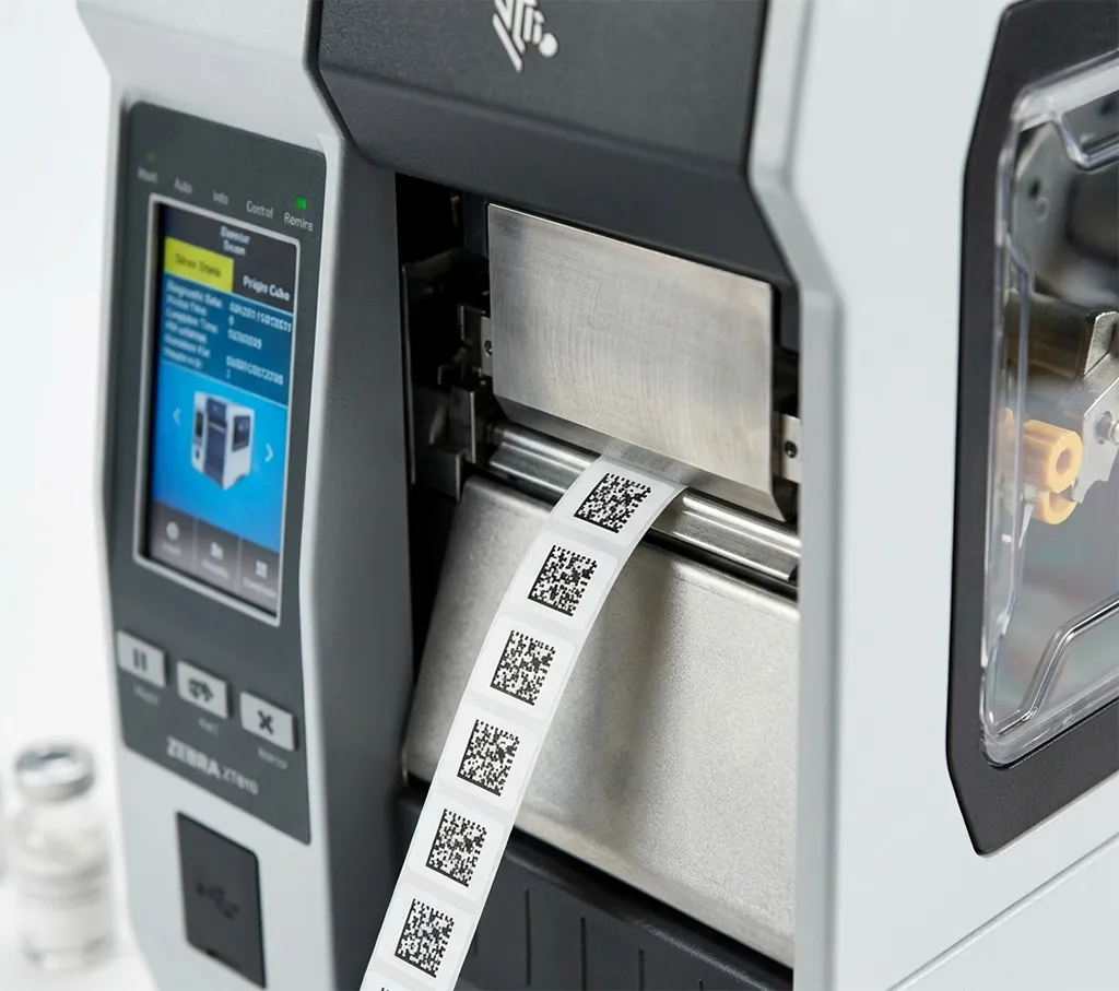 A Zebra ZT610 printer producing tiny micro-labels with high-density DataMatrix codes for pharmaceutical serialization.