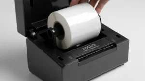A close-up photograph of a standard clear label roll being loaded into a Rollo X1040 printer, with a prominent "Direct Thermal Only" label on the machine's body.